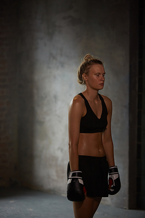 Candid portrait of tough female fighter at boxing practice, copy space