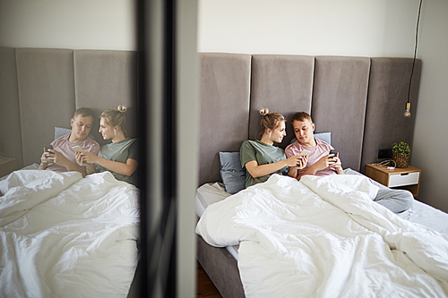 Contemporary young couple with smartphones discussing curious stuff in the net or social networks