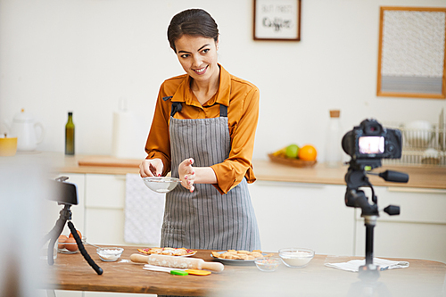 Waist up portrait of beautiful young woman  while filming baking tutorial for video channel, copy space