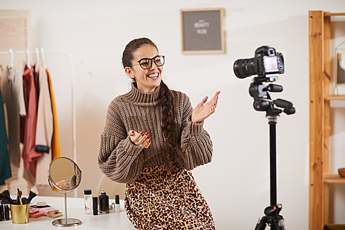 Portrait of contemporary young woman talking animatedly to camera while filming video vlog for beauty and lifestyle channel, copy space