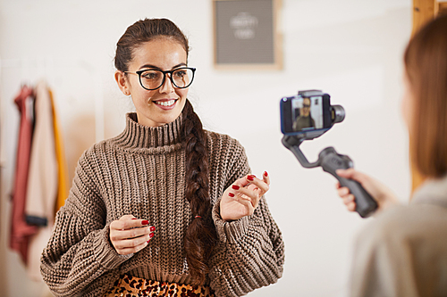Portrait of contemporary young woman talking animatedly to camera while recording video vlog for beauty and lifestyle channel