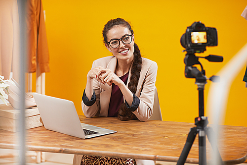 Portrait of contemporary young woman smiling at camera in studio while filming video for beauty and lifestyle channel, copy space