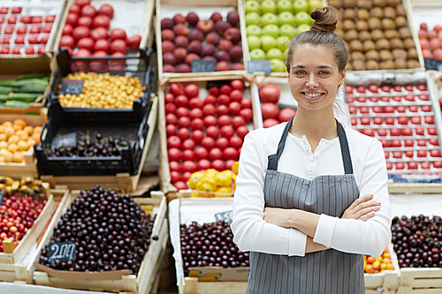 Waist up portrait of pretty young saleswoman posing with fresh fruits and vegetables at farmers market, copy space