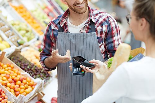 Mid section portrait of young woman paying via smartphone while grocery shopping in supermarket, copy space