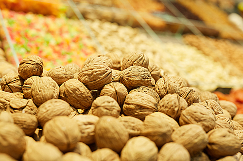Warm-toned background of heap of walnuts on dried fruit stand in farmers market or supermarket, copy space