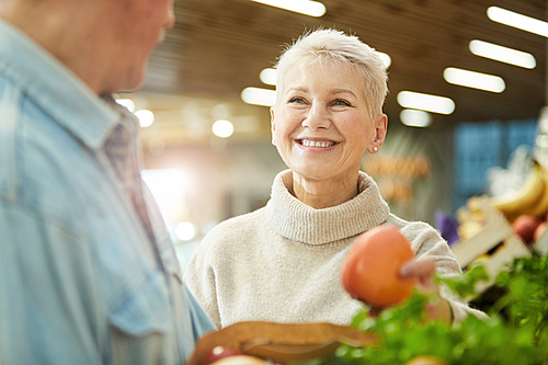 Portrait of smiling senior woman enjoying grocery shopping at farmers market with husband, copy space