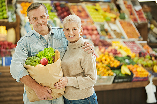 Waist up portrait of smiling senior couple  while enjoying grocery shopping at farmers market, copy space
