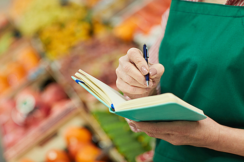 Close up of unrecognizable woman holding notebook while managing small business at farmers market, copy space