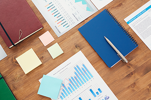 Graphic flat lay background of office workplace with statistic charts and documents on wooden table, copy space