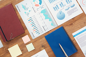 Flat lay background of office workplace with statistic graphs and documents on wooden table, copy space