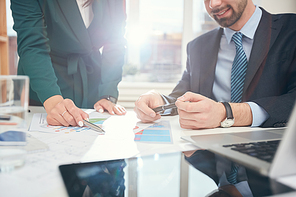 Background image of two successful business people pointing at data charts and graphs during meeting in office, scene lit by sunlight, copy space