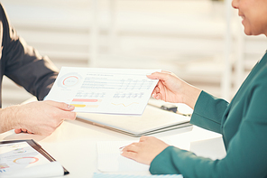 Closeup of unrecognizable businessmen handing documents during business meeting in office, copy space