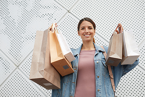 Young smiling woman happy with new clothes which she is holding in her hands in various shopping bags