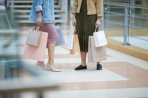 Unrecognizable woman with paper bags doing shopping with stylist in large mall