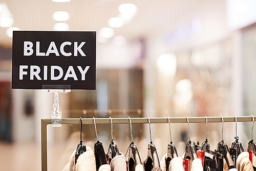 Background image of BLACK FRIDAY sigh on rack with clothes on sale in shopping mall, copy space