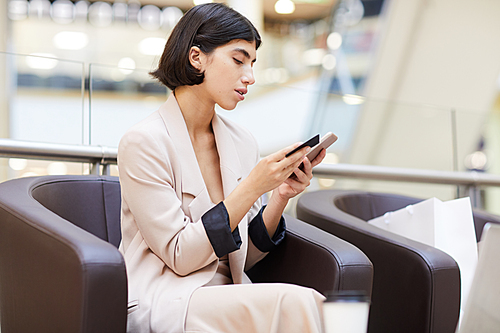 Side view portrait of elegant young woman holding credit card and smartphone while enjoying e-shopping, copy space