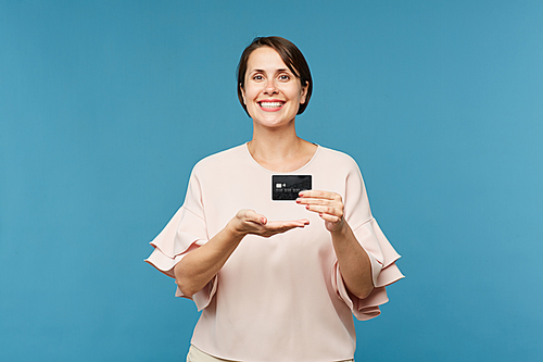 Young elegant woman in blouse showing you black credit card that can be used to pay for goods and services