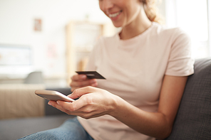 Close-up of positive woman using smartphone to link credit card to mobile wallet, she adding card number