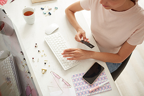 Above view of woman in casual tshirt sitting at table and checking order before online payment