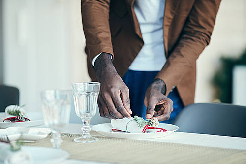 Close up of African-American man preparing table setting while decorating dining room for Christmas party at home, copy space