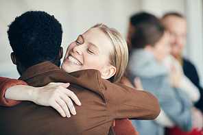 Portrait of smiling young woman hugging African-American friend while welcoming each other to party, copy space