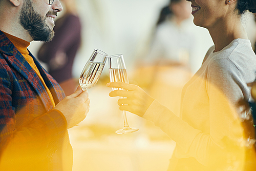Close up of adult couple drinking champagne and talking during Christmas party, golden flare overlay