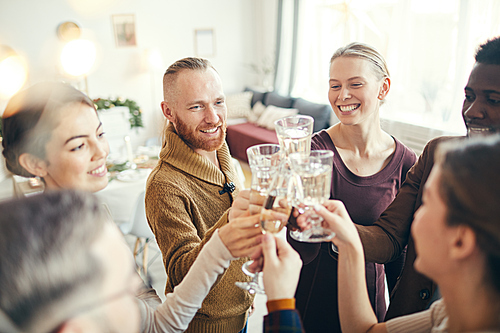 High angle view at group of elegant adult people clinking glasses during Christmas party in beautiful house, copy space