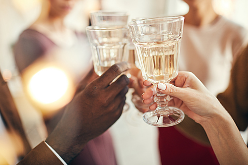 Close up of people clinking crystal glasses while celebrating at elegant Christmas party, copy space