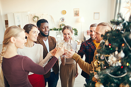 High angle view at elegant group of friends raising glasses while celebrating during Christmas party, copy space