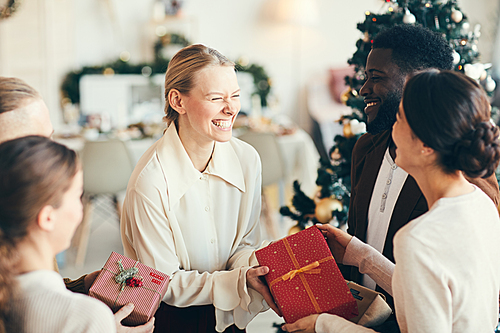 High angle portrait of elegant young people exchanging gifts and laughing happily during Christmas party, copy space