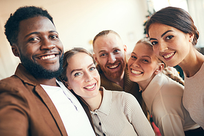 Multi-ethnic group of elegant adult people smiling at camera while taking selfie photo during Christmas party