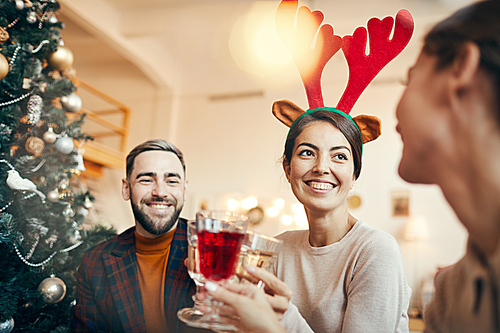 Portrait of beautiful young woman wearing funny deer horns celebrating Christmas with friends and family, copy space
