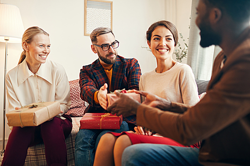 Portrait of elegant adult people exchanging gifts during Christmas party at home, copy space