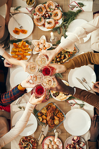 Above view background of people raising glasses over festive dinner table while celebrating Christmas with friends and family, copy space