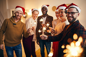 Multi-ethnic group of people holding sparkling lights and  while enjoying Christmas celebration with friends and family