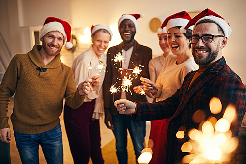 Multi-ethnic group of people holding sparkling lights and  while enjoying Christmas celebration with friends and family