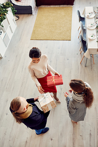 Above view at elegant young woman welcoming guests to Christmas party and receiving gift boxes, copy space