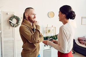 Waist up portrait of elegant young woman talking to friend while hosting Christmas party at home, copy space