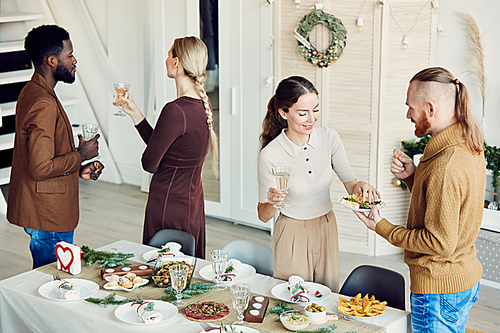 High angle portrait of elegant young people enjoying Christmas party and smiling happily while talking in dining room, copy space