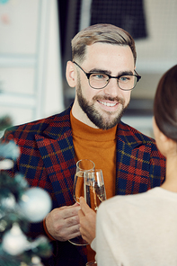 Portrait of handsome adult man smiling happily while talking to young woman and drinking champagne at elegant Christmas party