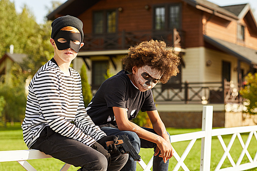 Portrait of two teenage boys wearing Halloween costumes posing outdoors and , copy space