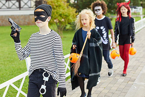 Group of children wearing Halloween costumes walking in row while trick or treating together