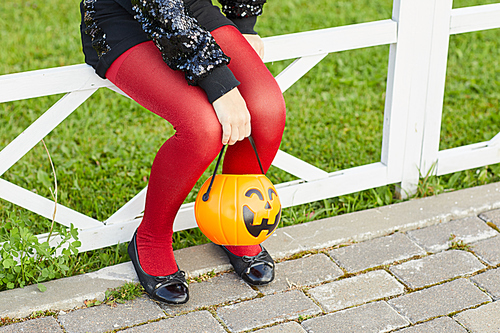 Low section portrait of unrecognizable girl holding pumpkin basket while trick or treating on Halloween, copy space