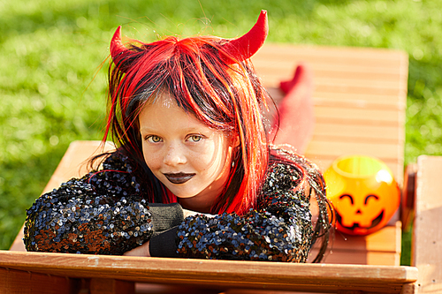 Portrait of cute girl wearing Halloween costume posing outdoors in sunlight while trick or treating, copy space