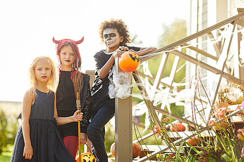 Multi-ethnic group of children trick or treating on Halloween, kids  while standing on stairs of decorated house, copy space