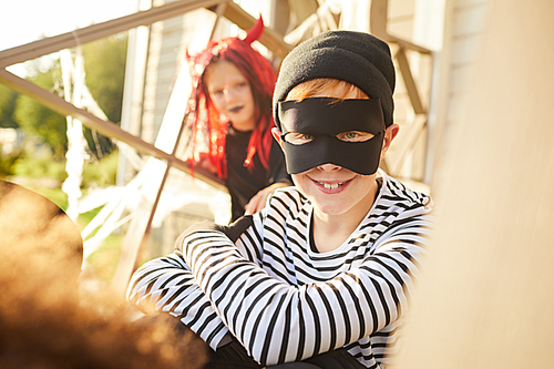 Portrait of cute little boy wearing Halloween costume  while sitting outdoors with friends, copy space