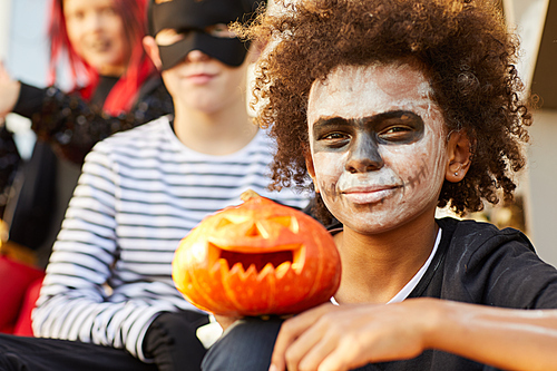 Portrait of African-American boy wearing Halloween costume  while sitting outdoors with friends, copy space