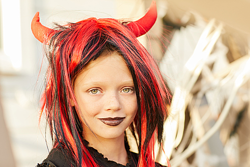 Head and shoulders portrait of cute little girl wearing Halloween costume  while posing outdoors in sunlight, copy space