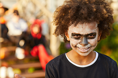 Head and shoulders portrait of happy African-American boy wearing Halloween costume  while posing outdoors , copy space