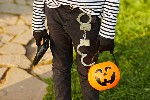 Close up of unrecognizable boy holding pumpkin basket while trick or treating on Halloween, copy space